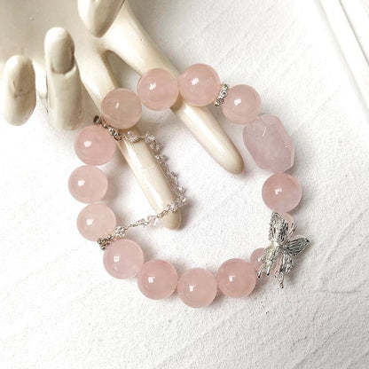beaded rose quartz bracelet with a silver butterfly charm on a white surface