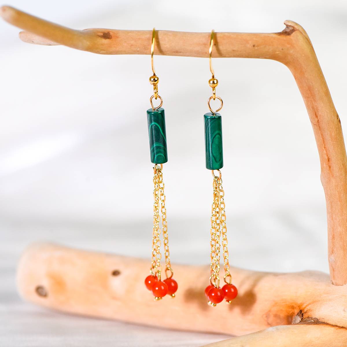 Gold chain earrings with Malachite and red beads on a wooden branch